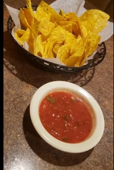 A basket of tortilla chips with salsa.
